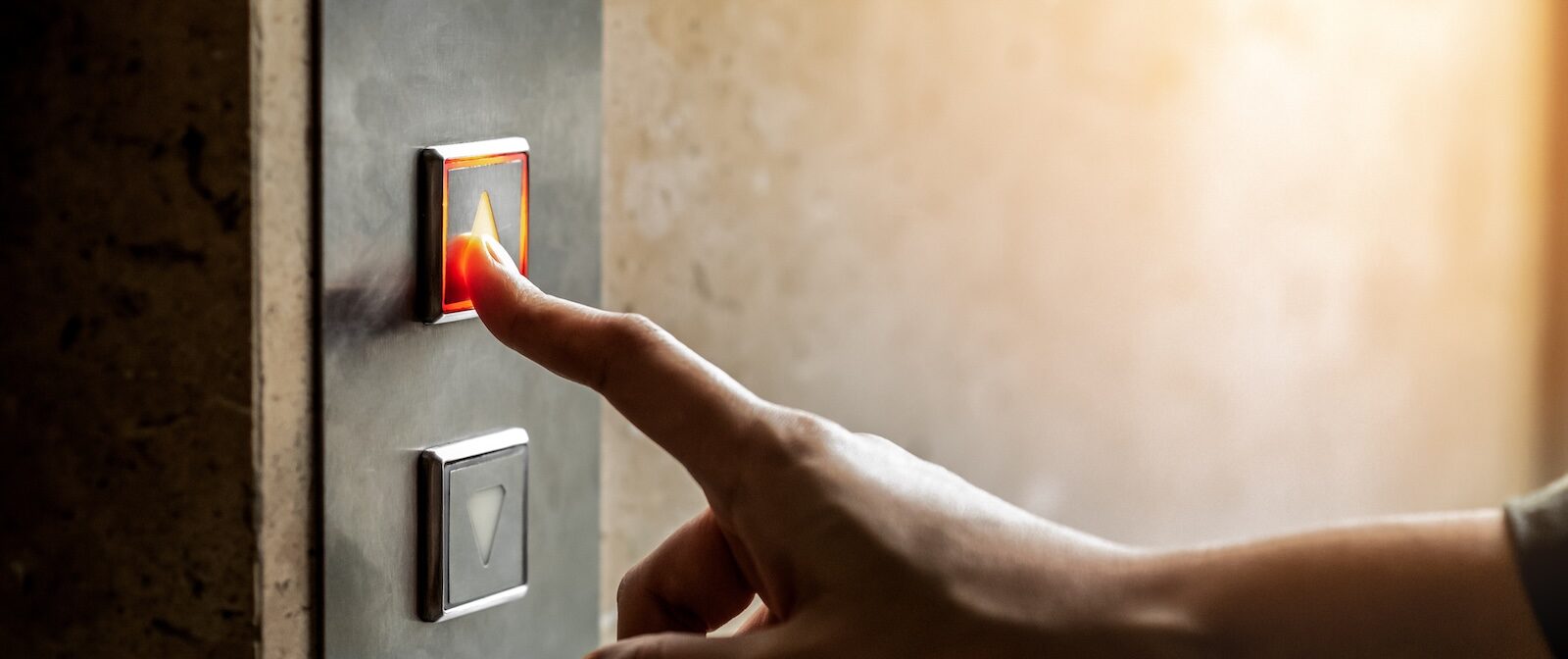 Woman's hand pushing up button in an elevator | Homes At Berry Ridge